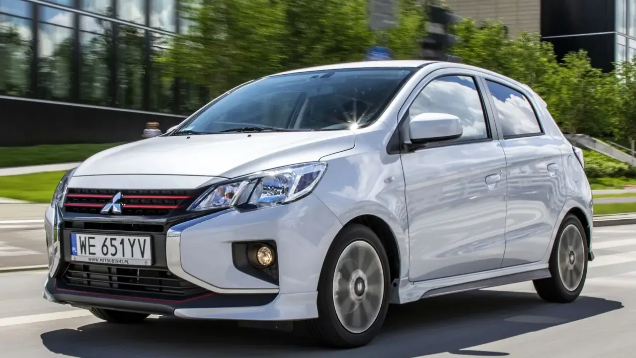 Srebrny Mitsubishi Space Star z czerwonymi akcentami na grillu i zderzaku jedzie po drodze.