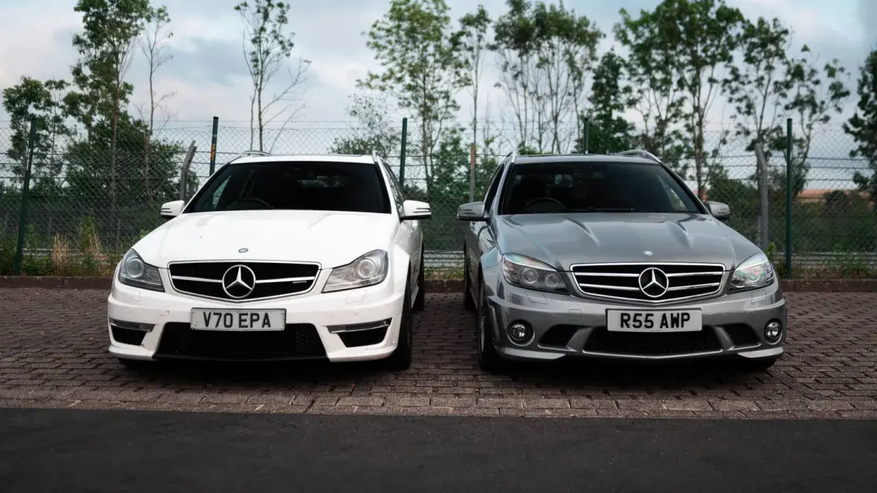 Dwa Mercedesy C63 AMG W204, biały i szary, stoją obok siebie na parkingu.