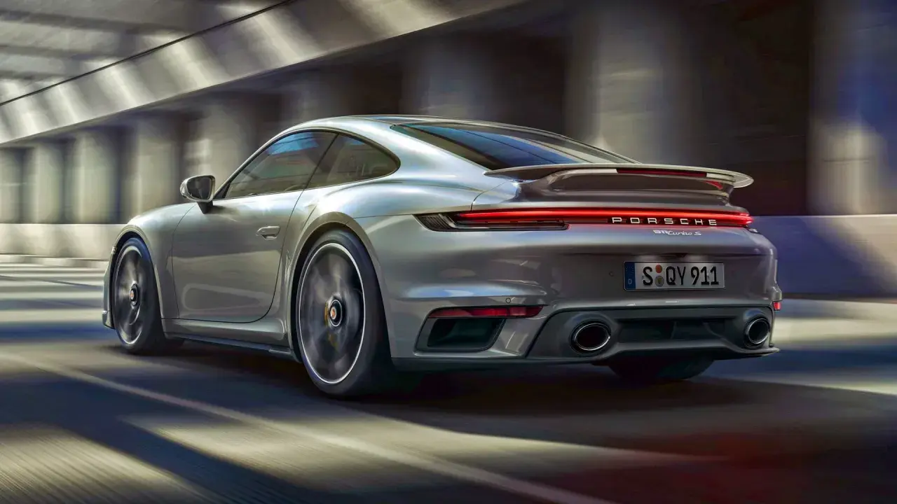 Srebrne Porsche 911 Turbo S pędzi przez tunel. Zastanawiasz się, ile kosztuje Porsche 911?