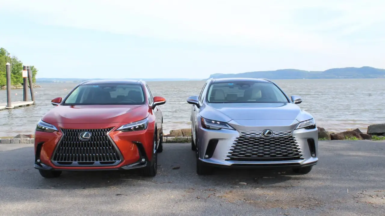 Dwa lśniące suvy Lexus stoją obok siebie nad wodą.