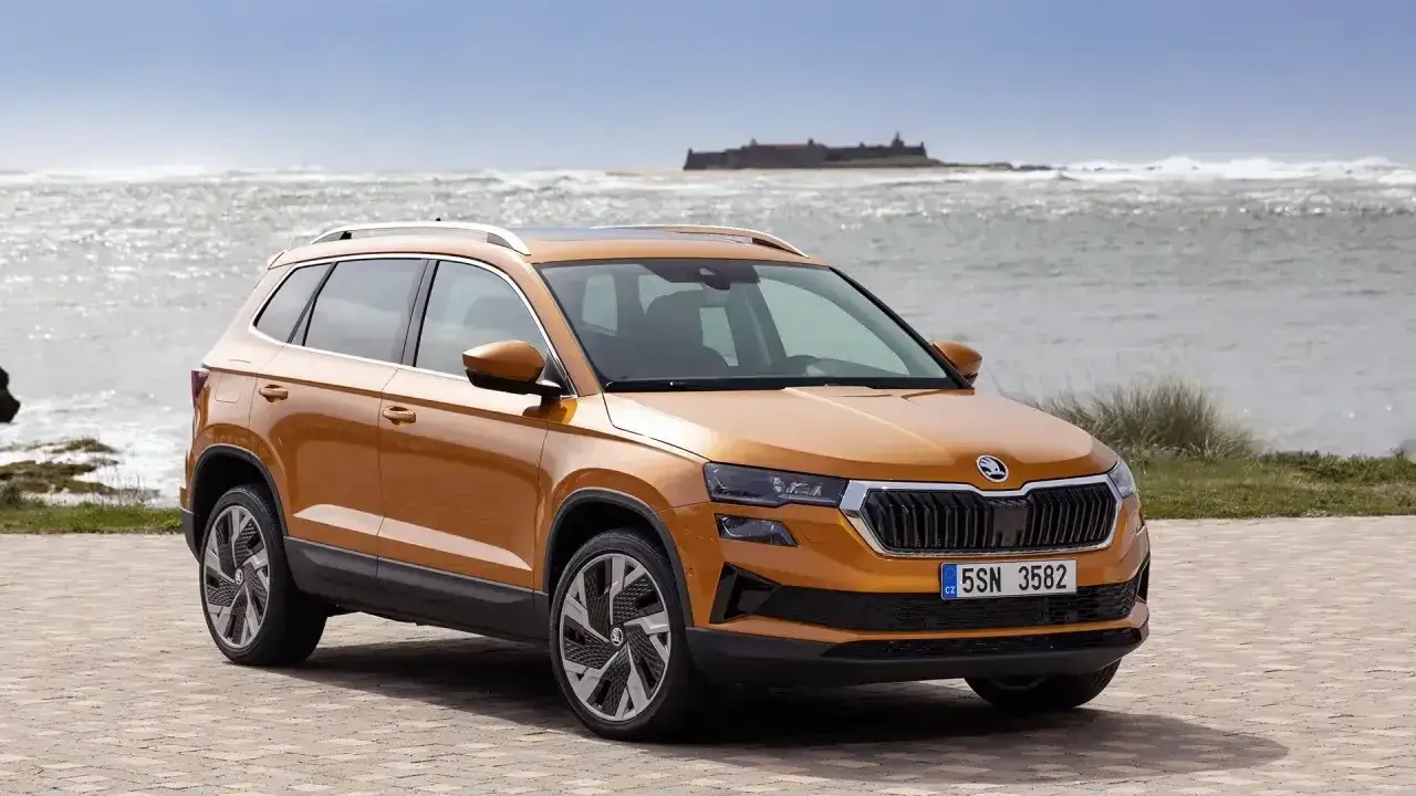 Pomarańczowy Skoda Karoq na tle morza. Sprawdź aktualną skoda karoq cena i wybierz swój wymarzony SUV.