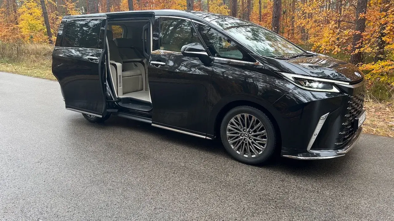 Elegancki Lexus LM 350h z otwartymi drzwiami, zapraszający do luksusowego wnętrza, na tle jesiennego lasu.