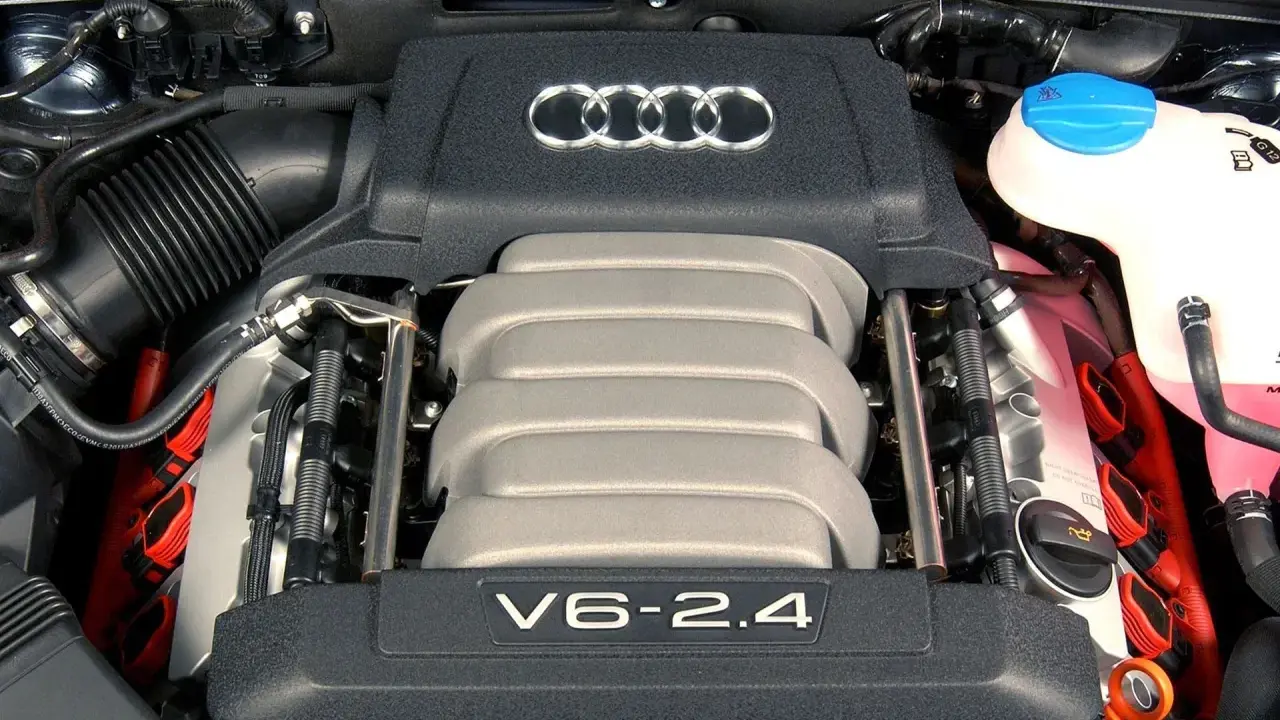 Silnik V6 2.4 z Audi C6. Widoczne logo Audi i elementy układu zapłonowego.