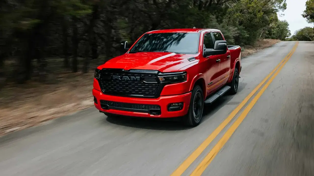 Czerwony Dodge Ram 1500 5.7 Hemi pędzi po krętej drodze wśród drzew.