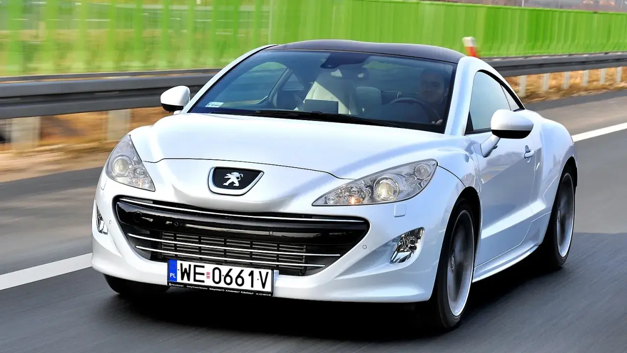 Biały Peugeot RCZ, jeden z francuskich marek samochodów, pędzi po autostradzie.