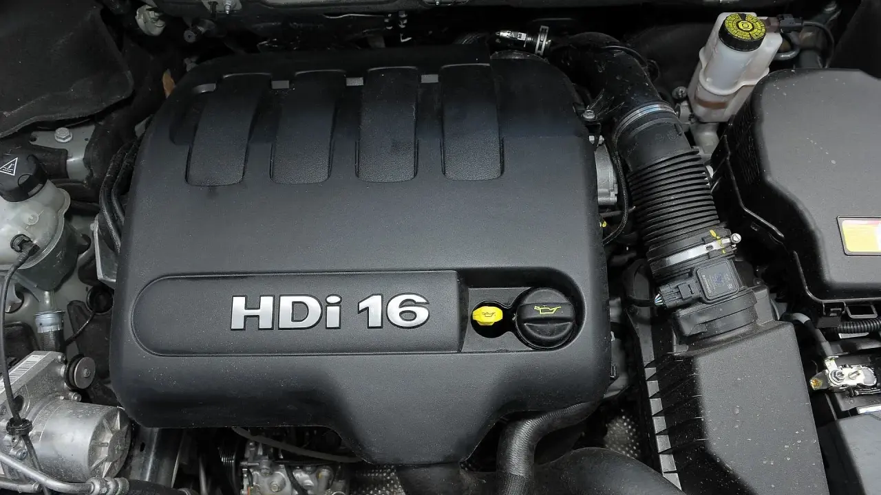 Silnik 2.0 HDi w Peugeot Expert. Widoczny czarny plastikowy dekiel z napisem HDi 16, żółty korek oleju i inne elementy komory silnika.