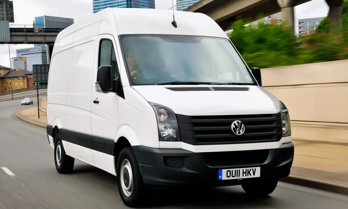 Biały Volkswagen Crafter w ruchu miejskim, z kierowcą za kierownicą.