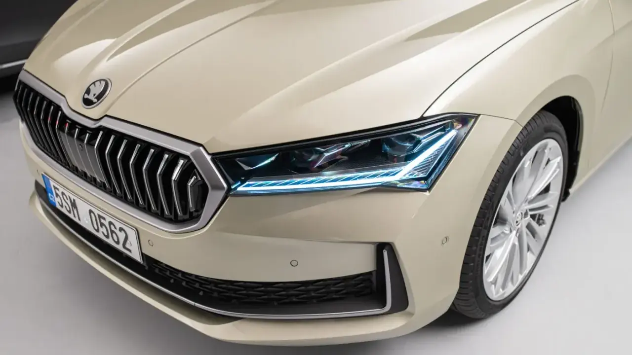 Nowy Skoda Superb 2024 w beżowym kolorze, z charakterystycznym grillem i nowoczesnymi światłami LED.