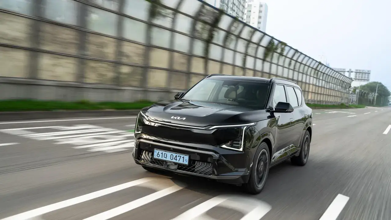 Nowoczesne kia ev5 w kolorze czarnym jedzie po drodze, mijając dźwiękochłonne bariery.