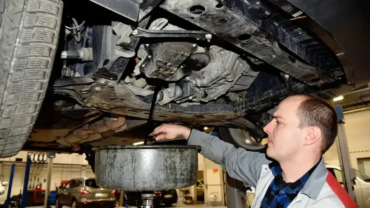 Mechanik wymienia olej w samochodzie. Regularna wymiana oleju co 15 tys. km lub raz w roku zapewnia płynną pracę silnika.