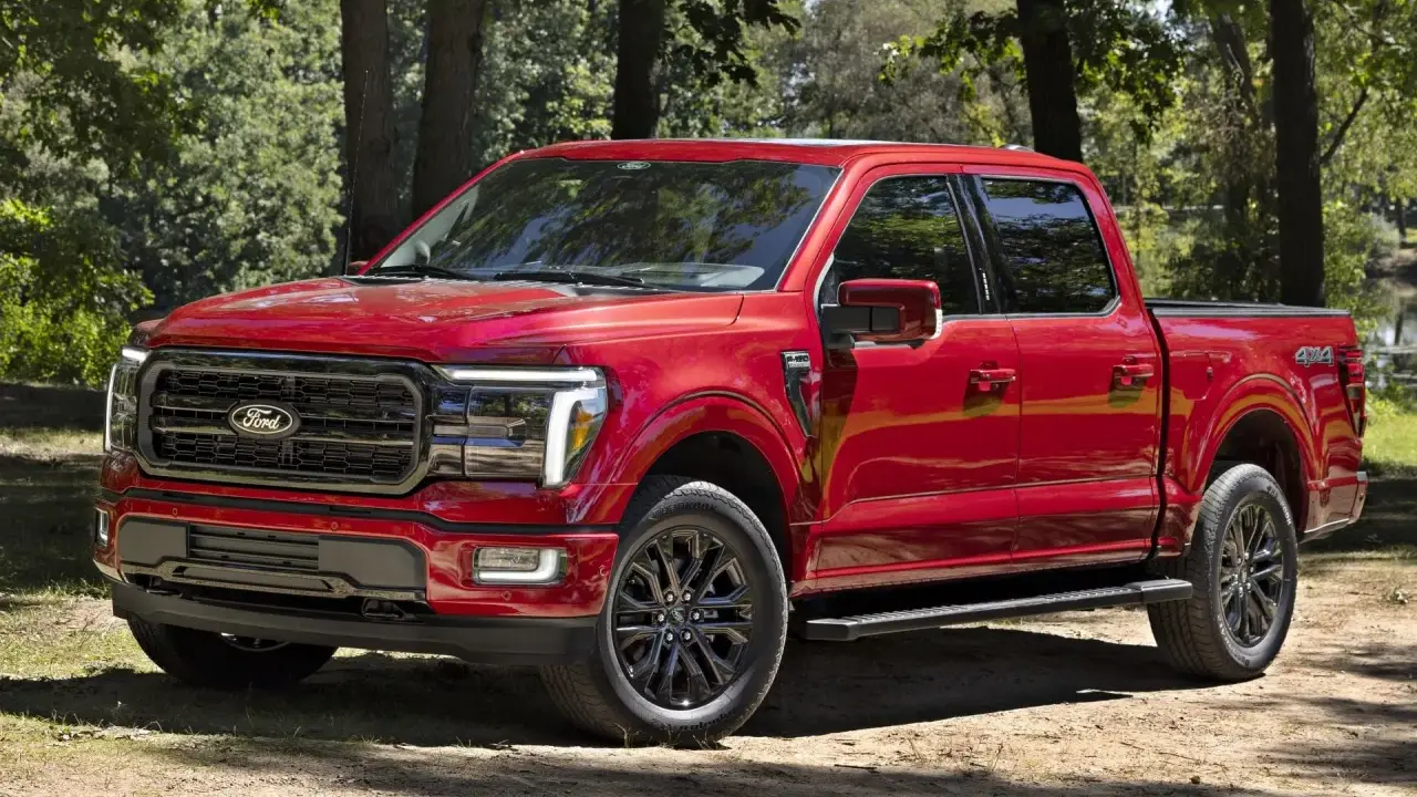 Czerwony Ford F-150 z czarnymi felgami stoi na leśnej ścieżce, gotowy na przygodę.