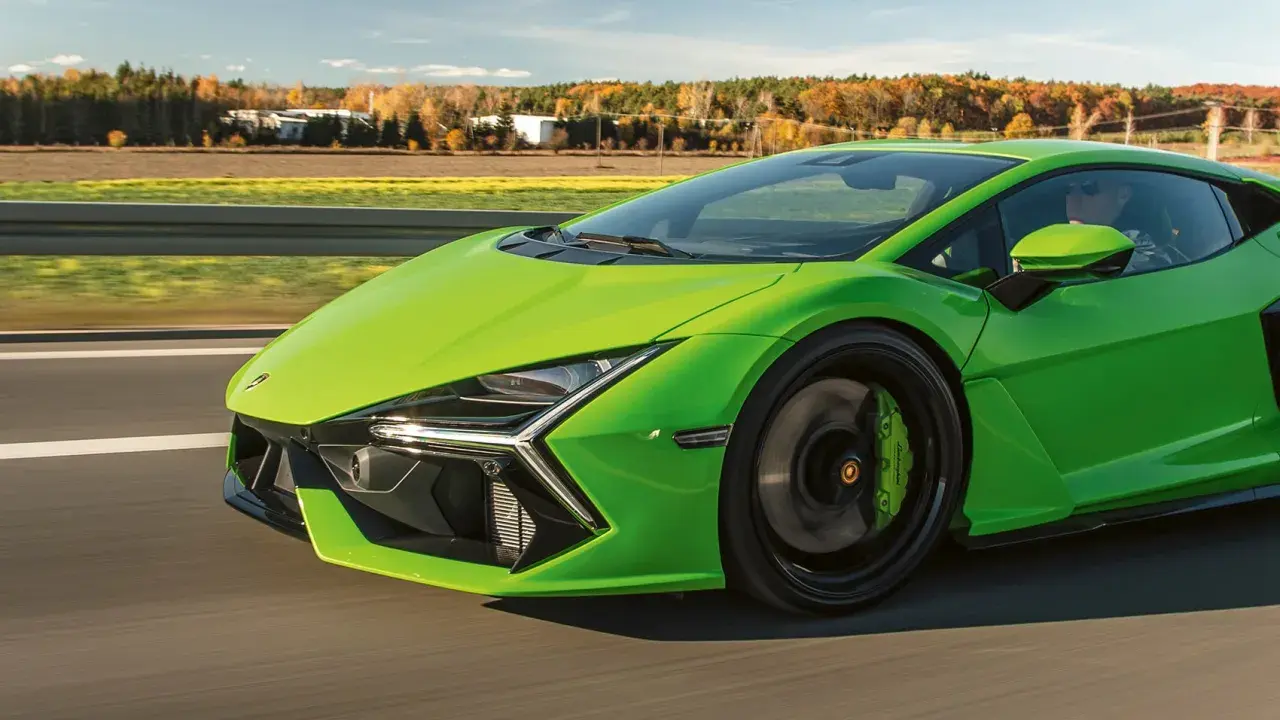 Jaskrawozielony Lamborghini Revuelto pędzi po drodze, ukazując swoje futurystyczne linie i sportowe detale.