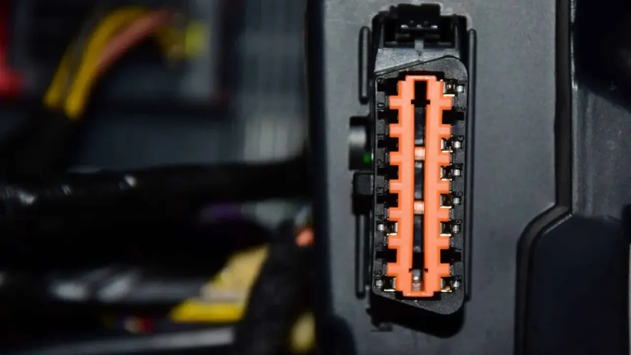 Pomarańczowe złącze diagnostyczne DTC w samochodzie, gotowe do podłączenia narzędzia diagnostycznego.