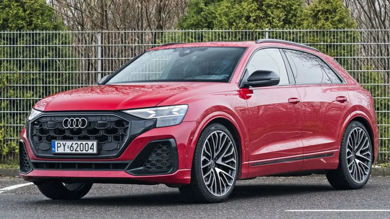 Czerwony Audi RS Q8 z czarnymi felgami stoi na parkingu.