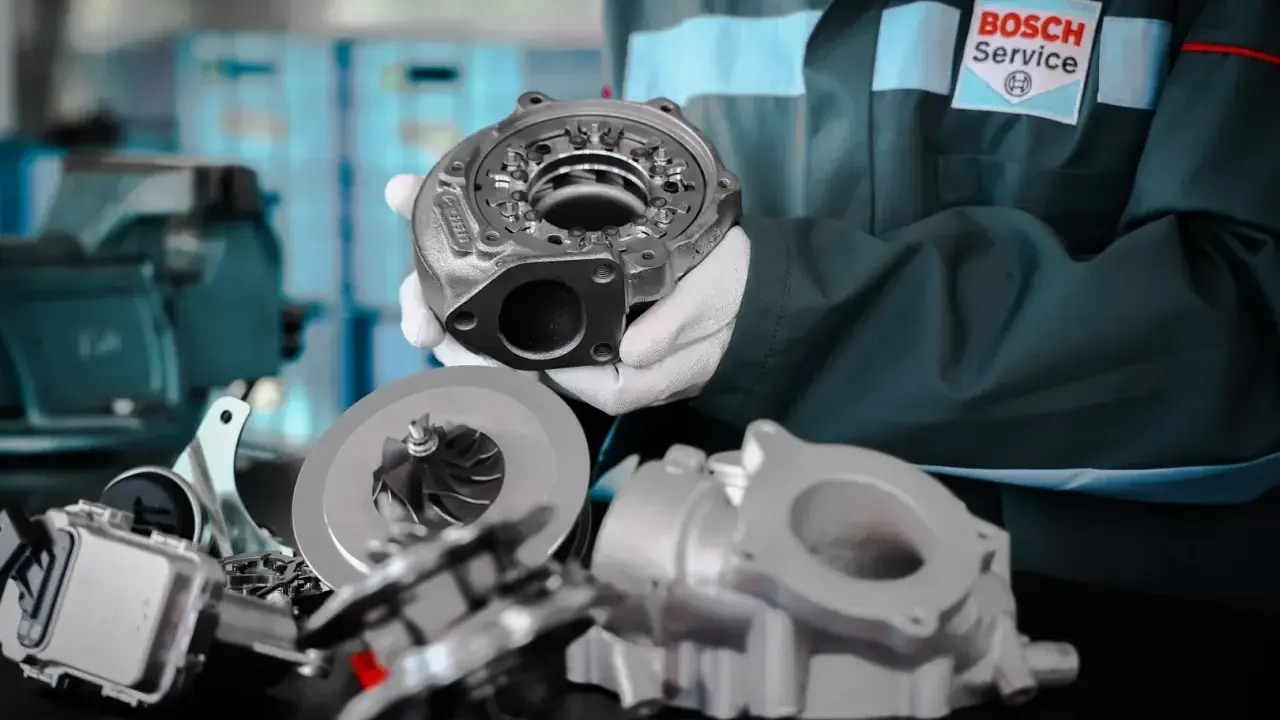 Mechanik w rękawiczkach prezentuje części turbosprężarki p0299. W tle logo Bosch Service.