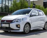 Srebrny Mitsubishi Space Star z czerwonymi akcentami na grillu i zderzaku jedzie po drodze.