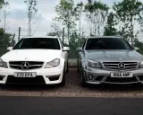 Dwa Mercedesy C63 AMG W204, biały i szary, stoją obok siebie na parkingu.