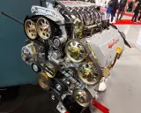 Silnik Alfa Romeo z widocznym układem rozrządu, kołami zębatymi i paskami. Widać napis "GTA 16V" i logo producenta. To serce potężnej maszyny, być może z legendarnym silnikiem hemi.