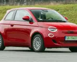 Czerwony fiat elektryczny 500 zaparkowany na tle zielonego wzgórza.
