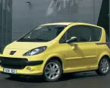Żółty Peugeot 1007 z przesuwnymi drzwiami stoi przed nowoczesnym budynkiem.