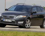Ciemnoszary Ford Mondeo MK4 2.0 TDCI na drodze, z widocznym polem zboża w tle.