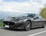 Szary Maserati GranTurismo na krętej drodze. Marzysz o takim aucie? Sprawdź, jaka jest aktualna maserati cena!