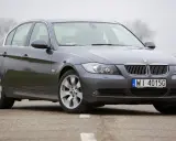 Szary sedan BMW E90 2.0 benzyna na drodze.