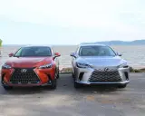 Dwa lśniące suvy Lexus stoją obok siebie nad wodą.