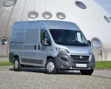 Srebrny Fiat Ducato 2.3 Multijet zaparkowany przed futurystycznym budynkiem z okrągłymi oknami.
