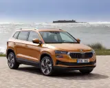 Pomarańczowy Skoda Karoq na tle morza. Sprawdź aktualną skoda karoq cena i wybierz swój wymarzony SUV.