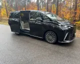 Elegancki Lexus LM 350h z otwartymi drzwiami, zapraszający do luksusowego wnętrza, na tle jesiennego lasu.