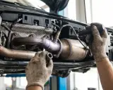 Mechanik sprawdza układ wydechowy Toyoty, potencjalnie diagnozując błąd DTC P0420.