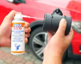 Czyszczenie przepływomierza preparatem Liqui Moly. W tle czerwony samochód.