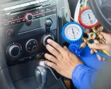 Mechanik sprawdza, ile czynnika do klimatyzacji pozostało w samochodzie, używając manometrów.