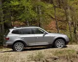 Srebrne BMW X3 E83 na leśnej ścieżce, gotowe na przygodę wśród drzew.