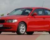 Czerwone BMW 116i z polskimi tablicami WI 3766G zaparkowane na czerwonym chodniku.