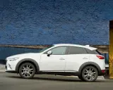 Biała Mazda CX-3 na tle niebieskiej ściany. Sprawdź aktualną mazda cx3 cena i wybierz swój wymarzony samochód.