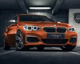 Pomarańczowe BMW 140i z tabliczką "SUPERCAR CLUB" stoi w garażu.
