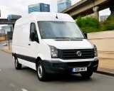 Biały Volkswagen Crafter w ruchu miejskim, z kierowcą za kierownicą.