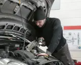 Mechanik z latarką bada silnik Renault, szukając przyczyny błędu DTC P0380.