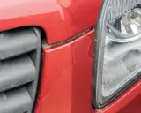 Pęknięty czerwony zderzak obok reflektora. Czas sprawdzić malowanie zderzaka cena.