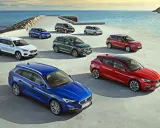 Różnorodne modele SEAT stojące nad morzem. Wśród nich biały SUV, niebieski kombi i czerwony hatchback.