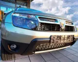 Złoty Dacia Duster 1.6 benzyna z bliska, z widocznym grillem, reflektorami i tablicą rejestracyjną.