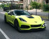 Jasnozielony Chevrolet Corvette C7 na brukowanej drodze. Zastanawiasz się nad corvette c7 cena?