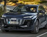 Ciemnogranatowy Audi Q6 e-tron jedzie po krętej drodze. Sprawdź atrakcyjną audi q6 e-tron cenę.