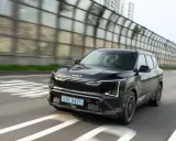 Nowoczesne kia ev5 w kolorze czarnym jedzie po drodze, mijając dźwiękochłonne bariery.