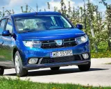 Niebieska Dacia Sandero 2025 jedzie przez kwitnący sad.