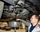 Mechanik wymienia olej w samochodzie. Regularna wymiana oleju co 15 tys. km lub raz w roku zapewnia płynną pracę silnika.