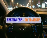 Widok na deskę rozdzielczą samochodu nocą. Na ekranie świeci się kontrolka ESP, a na kierownicy napis "SYSTEM ESP - CO TO JEST?".