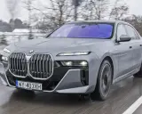 Szare BMW Serii 7 w ruchu, z widocznym grillem i światłami. Sprawdź aktualną bmw 7 cena.